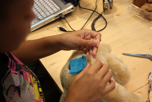 Sewing conductive thread to a teddy bear